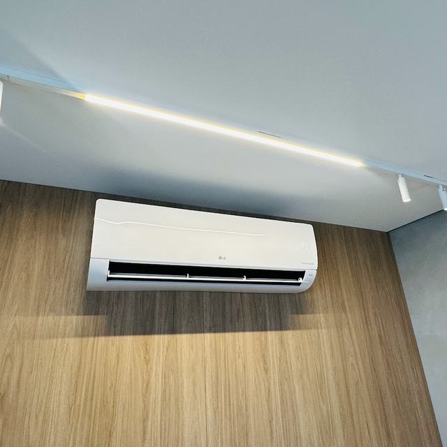 Split LG instalado em parede de painel de madeira, abaixo de trilho de luz