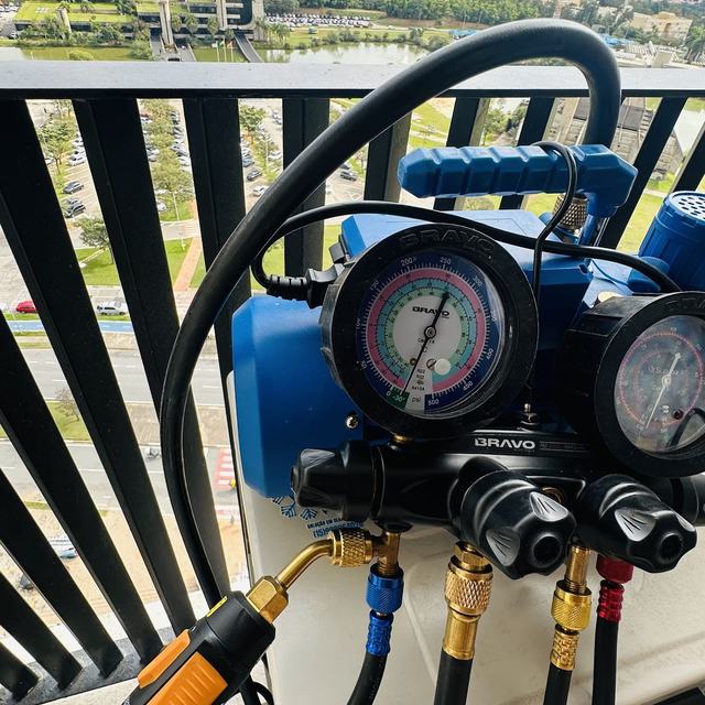 Manifold com manômetros e mangueiras conectado em sacada de apartamento alto
